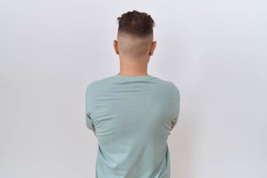 Beyaz arka planda duran sakallı İspanyol adam çapraz kollarla başka tarafa bakıyor. 