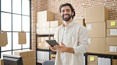 Latin kökenli genç bir iş adamı ofiste gülümseyen bir dokunmatik ped kullanıyor.