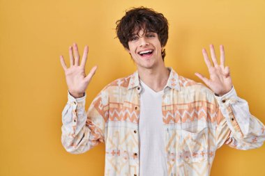 Gündelik tişört giyen genç adam dokuz numarayı gösterip işaret ederken kendinden emin ve mutlu gülümsüyor.. 