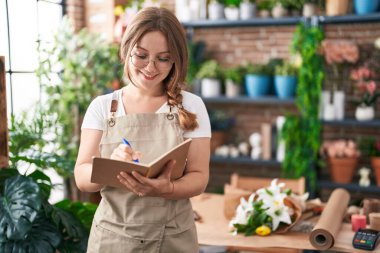 Çiçekçide kendine güvenen, gülümseyen sarışın bir kadın.