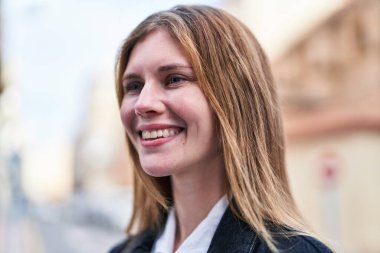 Young blonde woman smiling confident looking to the side at street