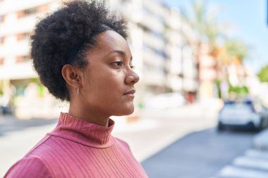 Sokakta ciddi bir ifadeyle yan tarafa bakan Afrikalı Amerikalı kadın.