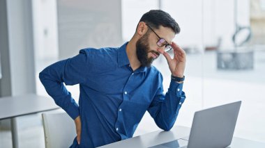 Genç İspanyol iş adamı. Ofiste sırt ağrısı çektiği için gözlüğünü çıkarıyor.