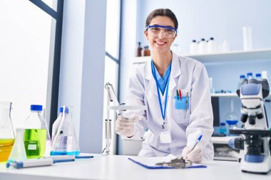 Genç, güzel İspanyol bilim kadını laboratuarda çalışan bir rapor yazıyor.