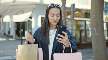 Kahve dükkanının terasında akıllı telefon kullanan genç ve güzel bir İspanyol kadın.