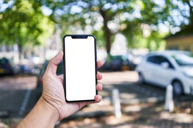 Elinde akıllı telefon tutan adam sokakta beyaz beyaz ekran gösteriyor