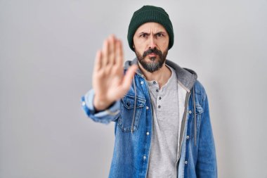 Yün şapkalı İspanyol genç adam avucunun içi gibi şarkı söylemeyi kesiyor. Yüzünde olumsuz ve ciddi bir jest olan uyarı ifadesi. 