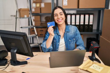 Young beautiful hispanic woman ecommerce business worker using laptop and credit card at office