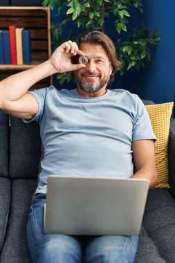 Orta yaşlı bir adam evinde Bitcoin 'i gözünün üstünde tutuyor.