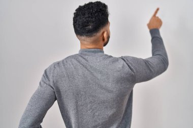 Beyaz arka planda dikilen sakallı İspanyol bir adam parmak ile öne doğru poz veriyor. 