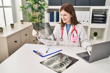 Genç sarışın doktor. Klinikteki masada oturuyor.