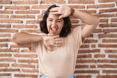 Tuğla duvarın üzerinde dikilen genç İspanyol kadın gülümseyen, güler yüzlü, elleri havada dikizcilik oynayan. Şaşırdım ve çıktım. 