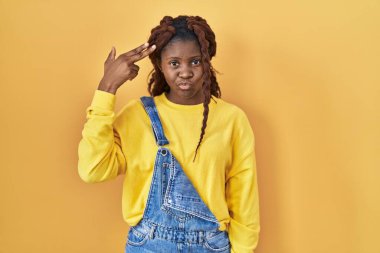 Afrikalı bir kadın sarı arka planda durup ateş ediyor ve kendini öldürüyor. Elini ve parmaklarını silah gibi kullanıyor. İntihar hareketi.. 