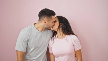 Kadın ve erkek, pembe arka planda öpüşürken gülümsüyor.