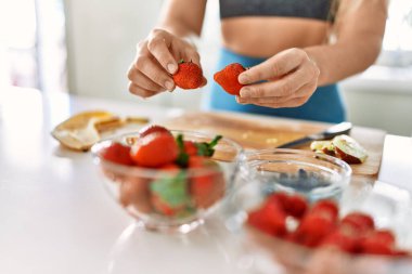 Mutfakta çilek saklayan genç bir kadın.