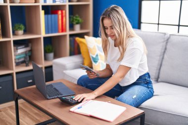 Evde dizüstü bilgisayar kullanan genç sarışın kadın.