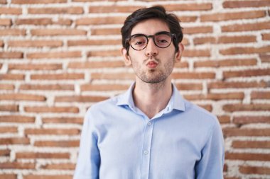 Duvarın arkasında dikilmiş, canlı yayında öpüşürken kameraya bakan Latin asıllı genç adam güzel ve seksi. aşk ifadesi. 