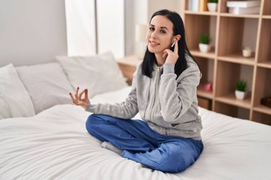 Young caucasian woman doing yoga exercise sitting on bed at bedroom