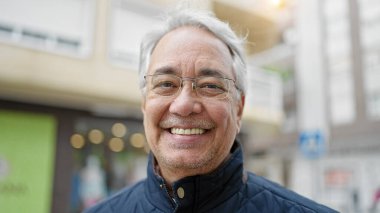 Orta yaşlı, gri saçlı, kendine güveni olan bir adam.