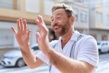 Middle age man smiling confident speaking at street