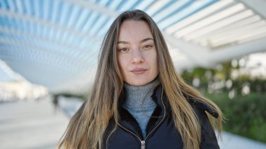 Young caucasian woman standing with serious expression at park