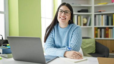 Kütüphanede bilgisayar kullanan genç İspanyol kız öğrenci.