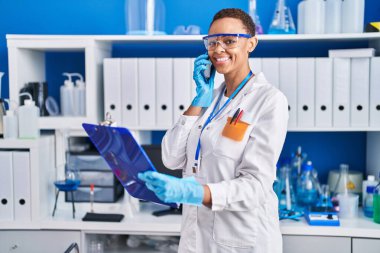 Afrika kökenli Amerikalı kadın bilim adamı laboratuvarda akıllı telefon okuyarak konuşuyor.