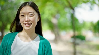 Parkta kendinden emin gülümseyen genç Çinli kadın.