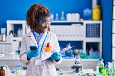 Laboratuvarda akıllı telefon okuma belgesi kullanan Afrikalı Amerikalı kadın bilim adamı.