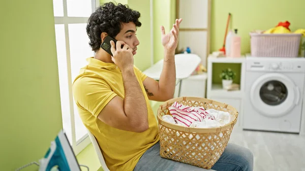 Genç Latin Adam Çamaşır Odasında Çamaşır Sepetiyle Akıllı Telefondan Tartışıyor — Stok fotoğraf