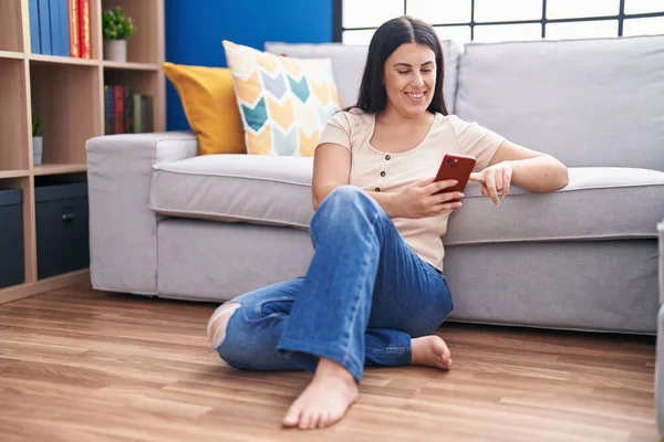 年轻美丽的惊慌失措的女人坐在家里的地板上用智能手机 — 图库照片