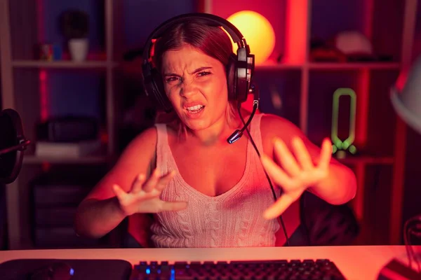 ヘッドフォンを着てビデオゲームをプレイする若い金髪の女性は恐れの表情でジェスチャーを停止し ショックで叫びます パニックコンセプト — ストック写真