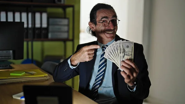 Middle age man business workers pointing to dollars smiling at the office