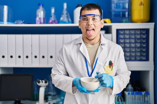 在科学家实验室工作的年轻的阿拉伯人带着好笑的表情伸出舌头 — 图库照片