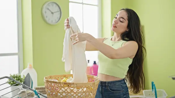 若い美しいヒスパニック系の女性が洗濯室でバスケットの服を保持 — ストック写真