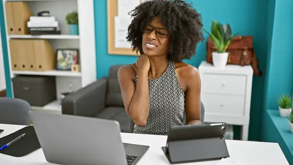 非洲裔美国女商人在办公室用触摸板和笔记本电脑治疗宫颈疼痛 — 图库照片