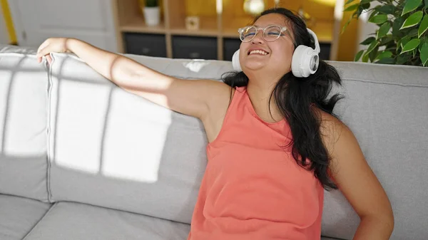 Νεαρή Κινέζα Που Ακούει Μουσική Καθισμένη Στον Καναπέ Στο Σπίτι — Φωτογραφία Αρχείου