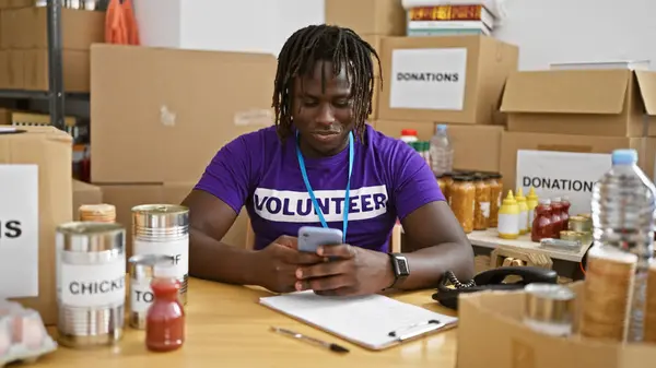 African american man volunteer smiling confident using smartphone at charity center