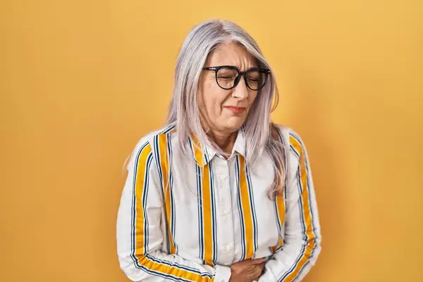 吐き気 痛みを伴う病気を感じるため 黄色い背景の上に立っている灰色の髪を持つ中年の女性 アチェのコンセプト — ストック写真