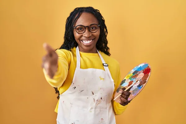 アフリカの女性は 挨拶と歓迎としてハンドシェイクを提供する笑顔の画家パレットを保持しています 成功したビジネス — ストック写真