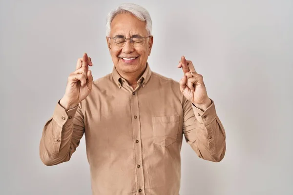 Hispanic Senior Man Wearing Glasses Gesturing Finger Crossed Smiling Hope — Stock Photo, Image