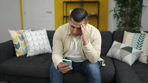Mladý Hispánec Používající Smartphone Sedí Pohovce Vypadá Rozrušeně Doma — Stock fotografie