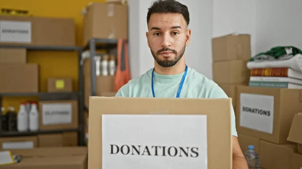 Young arab man volunteer holding donations package at charity center