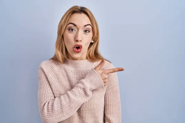 Hispanic Woman Standing Blue Background Surprised Pointing Finger Side Open — Stockfoto