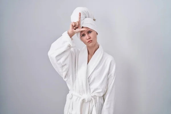 金发女人穿着浴衣取笑额头上有手指的人做失败者的手势嘲笑和侮辱 — 图库照片
