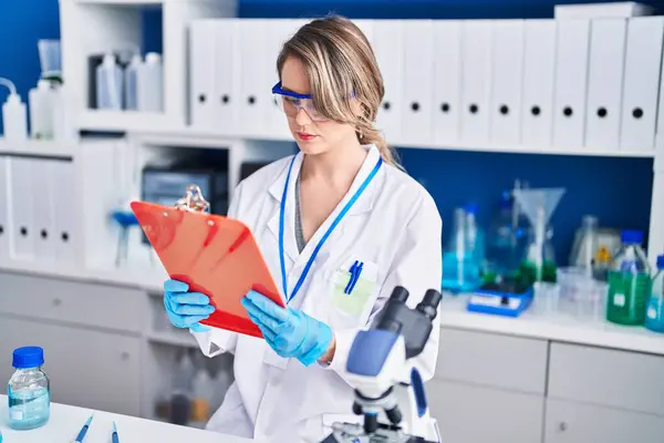 Young woman scientist reading report at laboratory