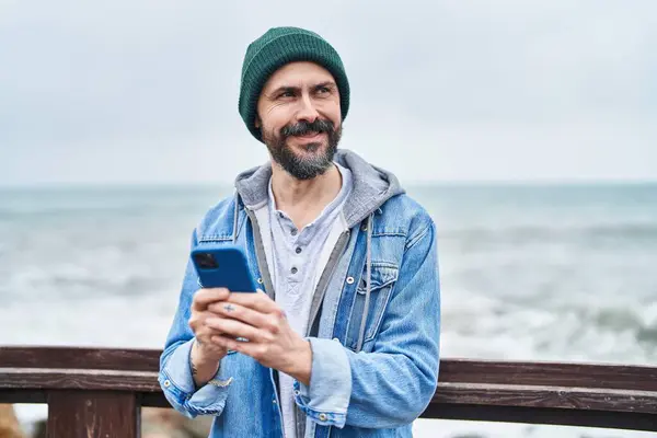 Young bald man smiling confident using smartphone at seaside