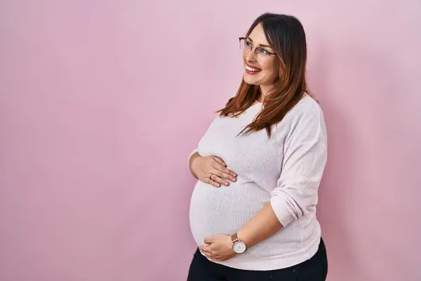 怀孕的女人站在粉红的背景上 面带微笑 自然地望向一旁 充满自信地大笑 — 图库照片