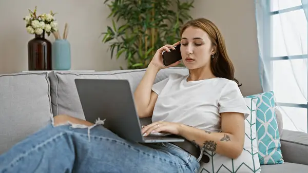 Akıllı Telefondan Konuşan Genç Bir Kadın Evde Dizüstü Bilgisayar Kullanıyor — Stok fotoğraf