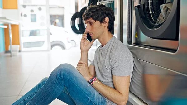 Ung Latinamerikan Man Talar Smartphone Lutar Sig Mot Tvättmaskin Tvättstuga — Stockfoto